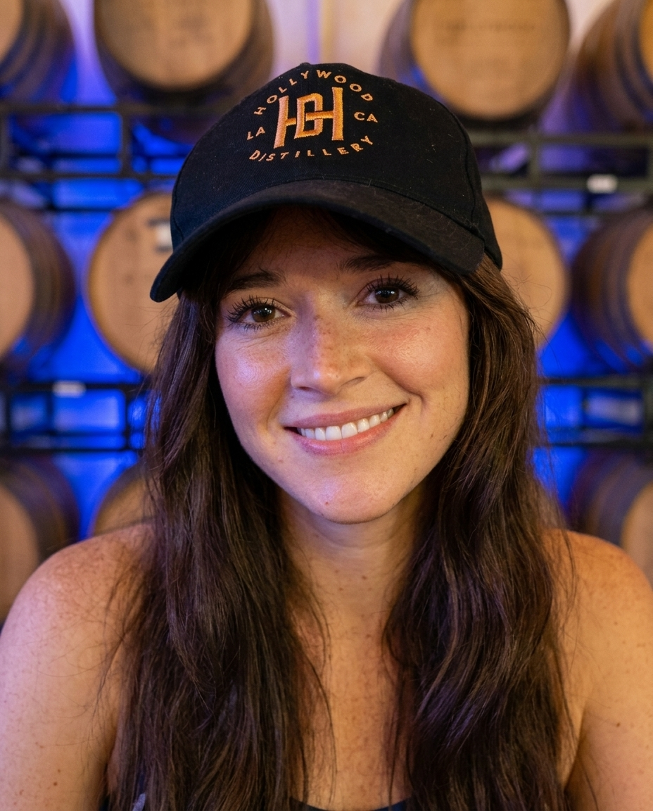 Model wearing the Hollywood Distillery Distillers Club logo cap in the barrel room