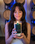 Model holding the lit Hollywood Distillery Gin candle in the barrel room