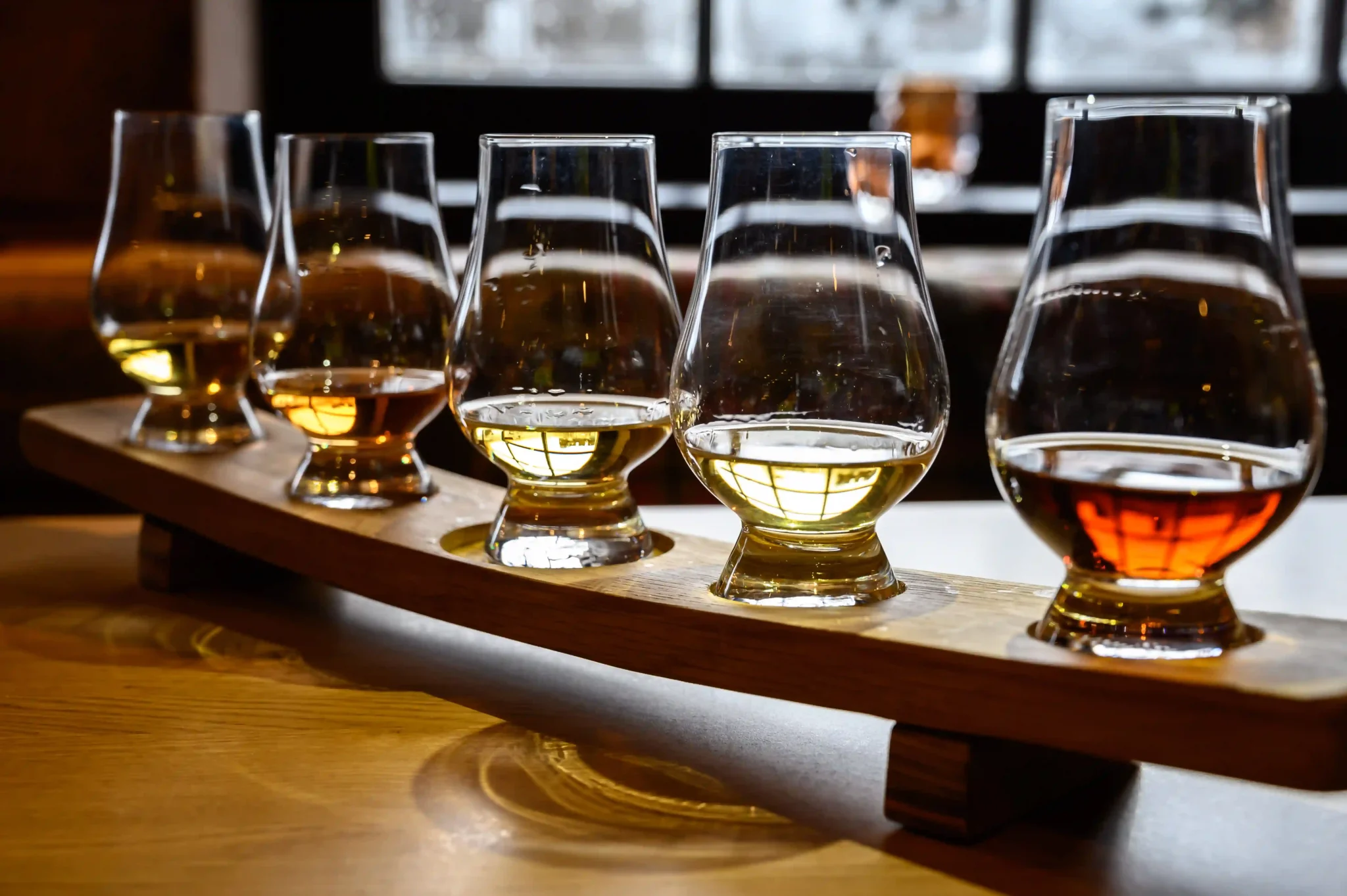 Different liquors in tasting glasses on a wooden tray