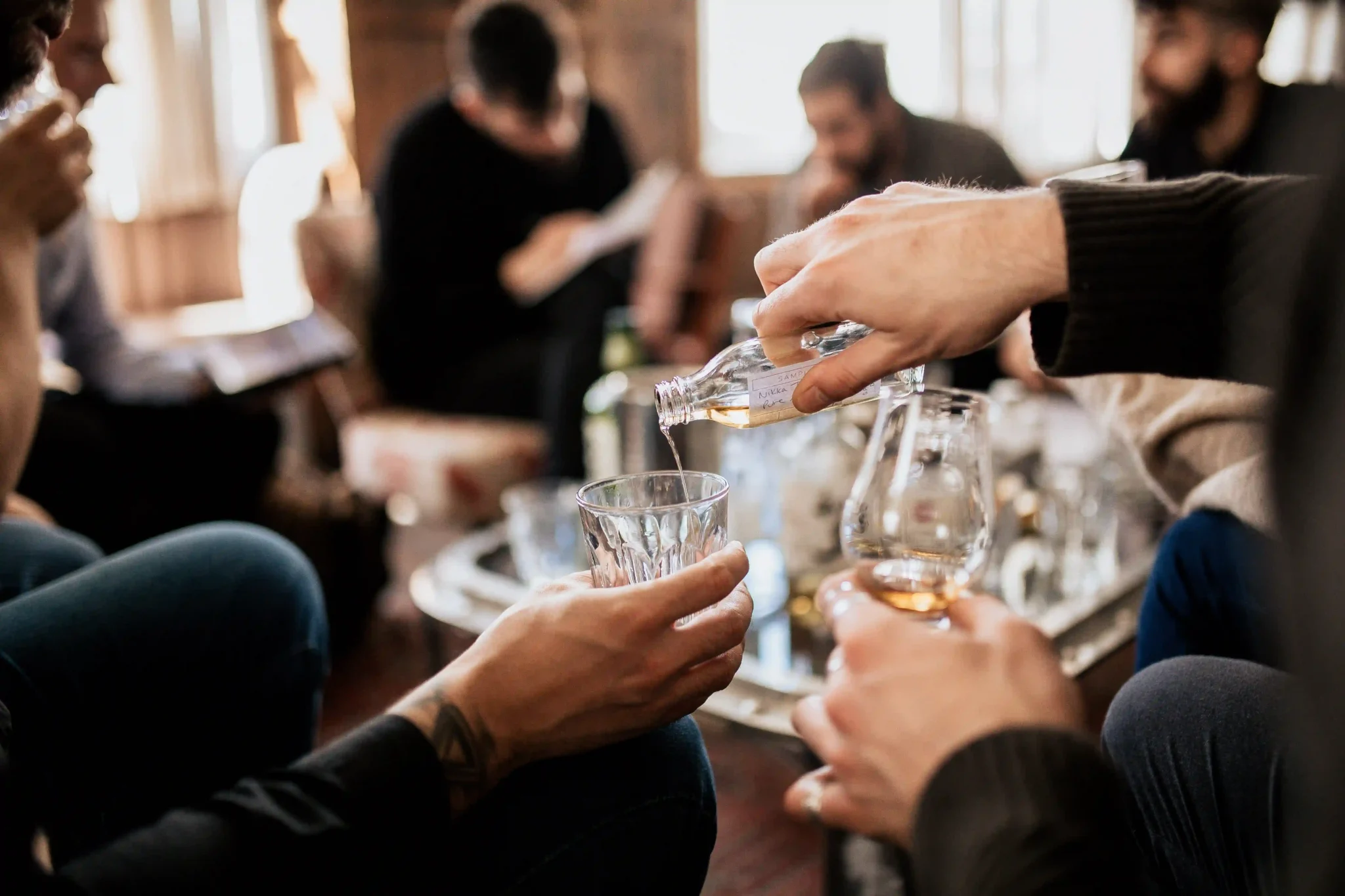 Man filling up another mans glass with liquor sample to let him try it